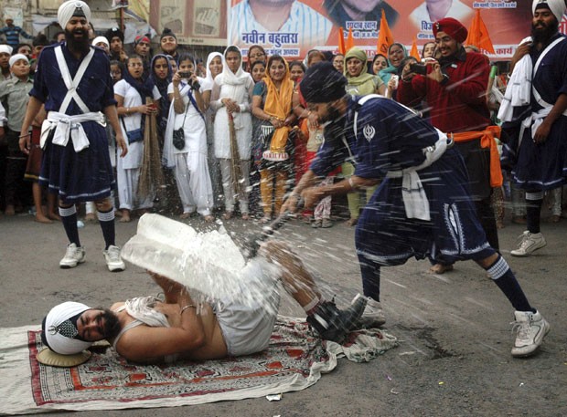 Guerreiros sikh indianos exibiram suas habilidades em artes marciais durante evento na segunda-feira (26) em Bhopal, na Índia. Em um dos números, um participante quebrou com uma marreta um bloco de gelo colocado sobre um colega. (Foto: Rajeev Gupta/AP)