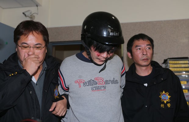 Suspeito foi hostilizado ao chegar na delegacia (Foto: Aden Hsu/AFP)