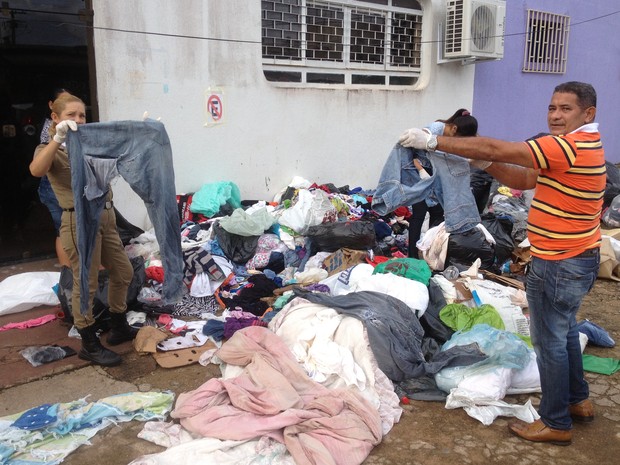 Voluntários mostram roupas rasgastas, já descartadas, embaladas como lixo, e extraviadas por moradores durante a madrugada (Foto: Assem Neto/G1 RO)