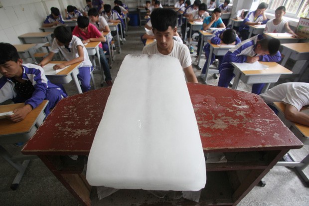 Estudante encara enorme barra de gelo colocada na sala. Temperaturas nas cidade de Jinan chegaram a 35,7º (Foto: AFP)