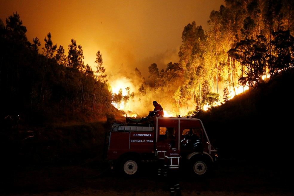 Bombeiros tentam combater o incêndio florestal perto de Bouca, na região central de Portugal, na madrugada deste domingo (18) (Foto: Rafael Marchante/Reuters)