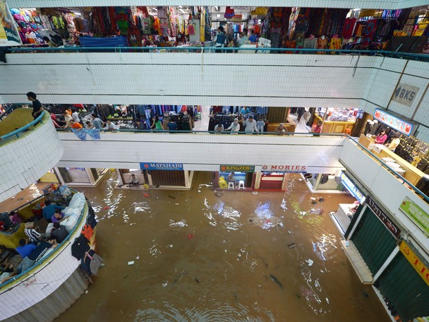 Lojas do mercado Cipulir de produtos têxteis, em Jacarta, segue funcionando normalmente mesmo parcialmente alagado. (Foto: Adek Berry/AFP)