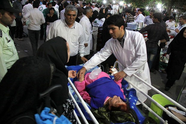 Médico atende mulher ferida do lado de fora de hospital em Ahar, cidade iraniana afetada por terremoto neste sábado (11) (Foto: Kamel Rouhi / AFP)