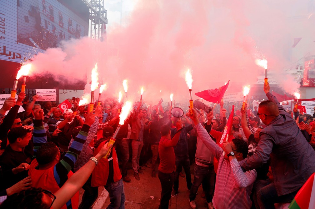 Membros da União Geral dos Trabalhadores Tunisiana (UGTT, na sigla em inglês) seguram sinalizadores e bandeiras durante marcha para marcar o Dia do Trabalhador em Tunis nesta segunda-feira, dia 1º de maio de 2017 (Foto: Zoubeir Souissi/Reuters)