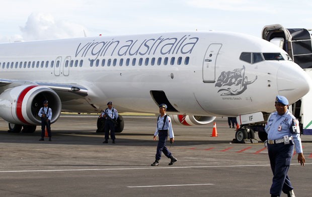 Integrantes da Força Aérea da Indonésia são vistos ao lado do avião da Virgin Australia que sofreu um alerta de tentativa de sequestro nesta sexta-feira 25). Um passageiro bêbado e alterado tentou invadir a cabine do piloto. O avião pousou em segurança e  (Foto: Firdia Lisnawati/AP)