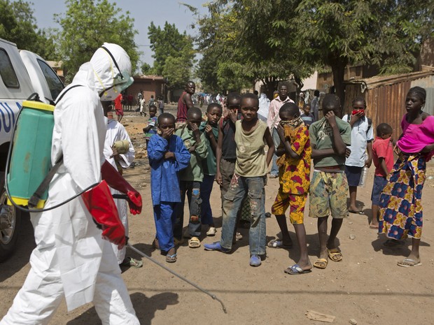 Crianças observam agente pulverizando desinfetante no lado de fora de uma mesquita como parte da luta contra o Ebola, em Bamako, no Mali, no início de novembro (Foto: Joe Penney/Reuters)