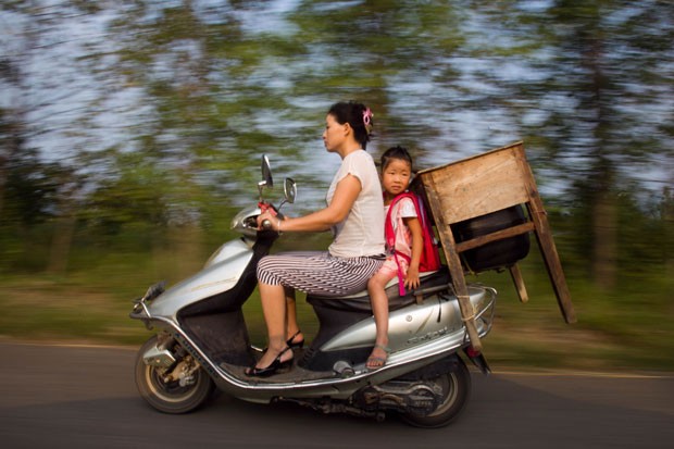 Mãe foi flagrada transportando a filha e uma mesa em uma motoneta. (Foto: AFP)