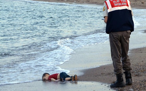 Oficial encontra corpo sem vida de uma criança refugiada, que morreu enquanto seguia para ilha grega de Kos (Foto: AP Photo/DHA)