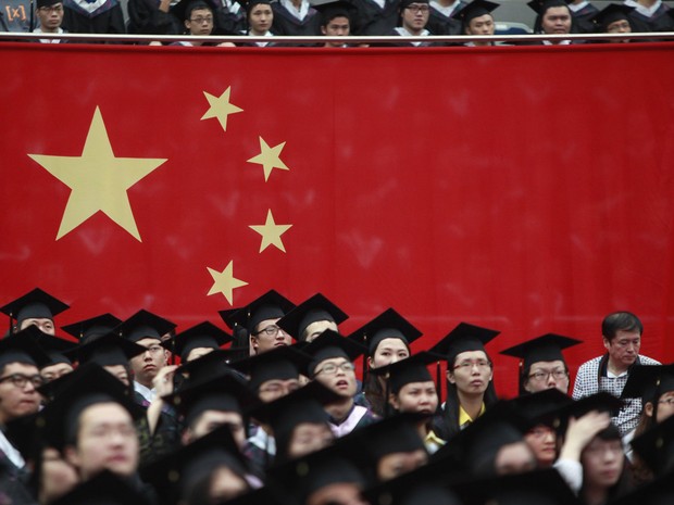 Alunos assistem ao lado da bandeira chinesa a cerimônia de graduação na Universidade de Fudan, em Xangai. (Foto: Aly Song/Reuters)