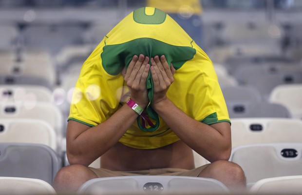 Torcedor cobre o rosto após derrota histórica da Seleção Brasileira. Nunca o Brasil tinha tomado sete gols em uma partida de Copa do Mundo (Foto: Frank Augstein/AP)