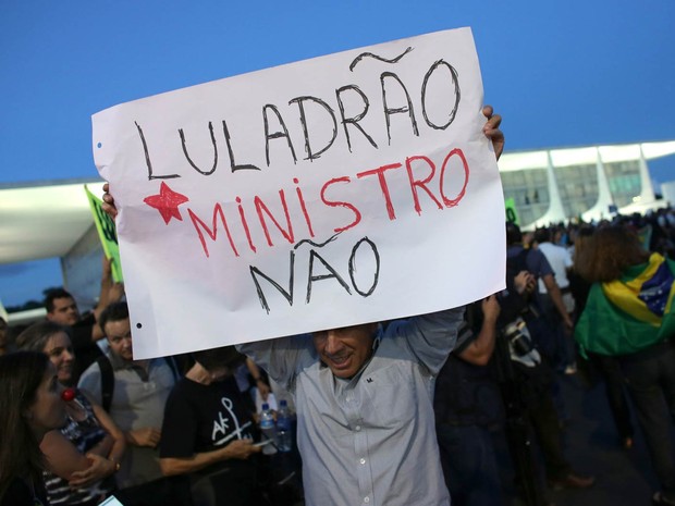 Manifestante ergue cartaz em protesto contra a nomeação do ex-presidente Lula como ministro da Casa Civil, em frente ao Palácio do Planalto (Foto: Eraldo Peres/AP)