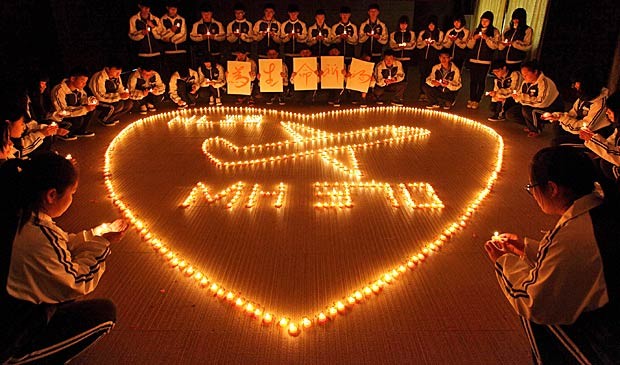 Jovens alunos da escola internacional de Hailiang, em Zhejiang, na China, acendem velas e rezam pelos passageiros do voo desaparecido da Malaysia Airlines. (Foto: AFP Photo)