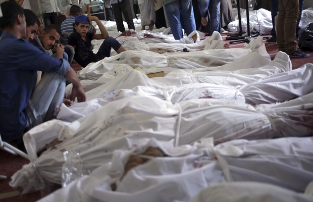 Familiares lamentam a morte de entes queridos mortos durante operação policial que destruiu acampamentos da Irmandade Muçulmana no Cairo, Egito. Ao menos 525 partidários do presidente deposto Mohamed Morsi morreram durante o conflito, na quarta-feira (14) (Foto: AP Photo/Khalil Hamra)