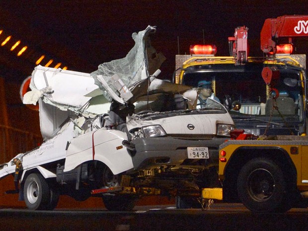 Carro destruído por desabamento de túnel no Japão é retirado do local nesta segunda-feira (3) (Foto: AP)