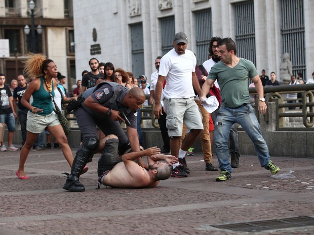 Policial aponta arma para pessoa após apartar briga no Viaduto do Chá (Foto: Marcelo Brandt/G1)