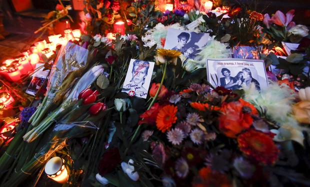 Flores e velas acesas ao lado de um retrato de David Bowie do lado de fora do prédio em que o cantor viveu em Berlim, na Alemanha (Foto: REUTERS/Hannibal Hanschke )