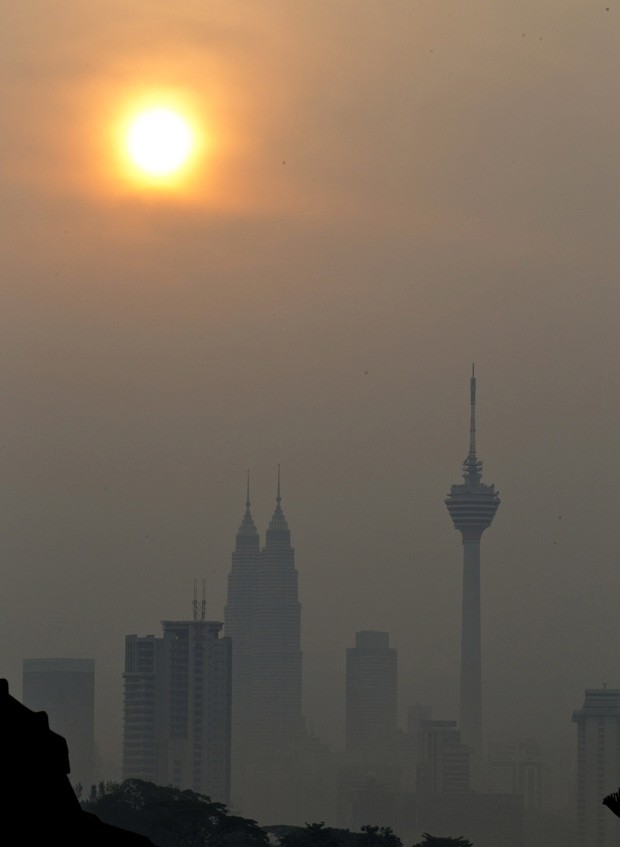 Imagem da capital da Malásia, Kuala Lampur, com espessa camada de poluição, durante o amanhecer deste domingo (17), noite de sábado no Brasil (Foto: Mark Baker / AP)