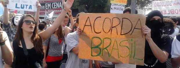 Jovens exibem cartaz de protesto durante o desfile (Foto: Marcos Pacheco/RBS TV)