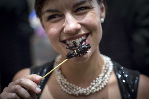 Mulher prova um espetinho de tarântula no 110º Jantar Anual do Explorers Club (Foto: Andrew Kelly/Reuters)