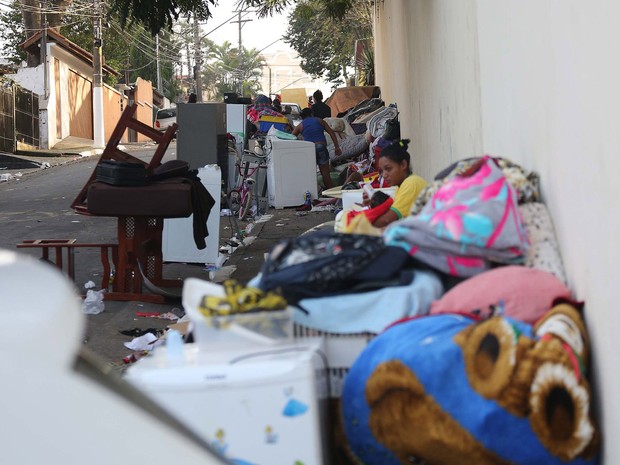 Mulher alimenta bebê enquanto moradores cuidam de seus pertences amontoados em uma calçada na manhã seguinte ao incêndio na favela conhecida como Buraco Quente, no Campo Belo, em São Paulo. Cerca de 600 famílias ficaram desalojadas (Foto: Renato S. Cerqueira/Futura Press/Estadão Conteúdo)