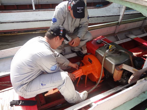 Equipe da Capitania dos Portos colocando a proteção de metal no motor de um barco na Feira do Açaí, no complexo do Ver-o-peso, em Belém (Foto: Natália Mello/G1)