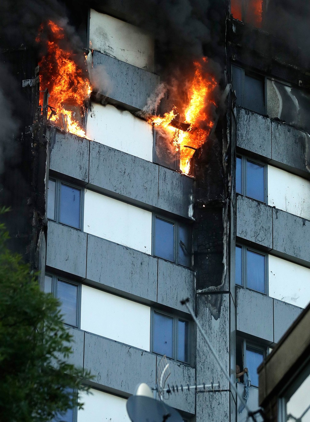 Pessoa sinaliza estendendo uma peça de roupa do lado de fora da janela enquanto incêndio toma conta da Torre Grenfell, em Londres (Foto: Matt Dunham/AP)