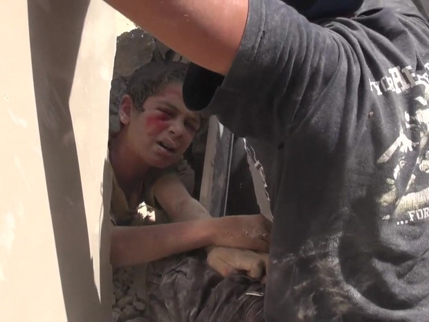 Ahmad, de 11 anos, ficou preso em meio aos destroços de um prédio atingido por um ataque aéreo (Foto: BBC)