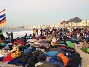 Peregrinos observam o amanhecer na praia de Copacabana após passarem a noite em vigília. (Foto: Eduardo Carvalho/G1)