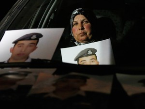Me do piloto sequestrado pelo Estado Islmico Muath al-Kasaesbeh exibe fotos do filho durante uma manifestao em frente  casa do primeiro-ministro em Am. Ela exige que o governo jordaniano negocie com o Estado Islmico para o liberao de Muath (Foto: Muhammad Hamed/Reuters)
