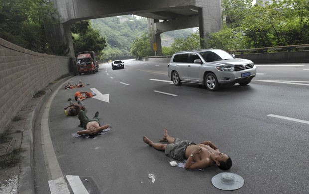 23 de julho -  Operários chineses se arriscaram e foram flagrados tirando uma soneca deitados em uma estrada em Chongqing, na China (Foto: Stringer/Reuters)
