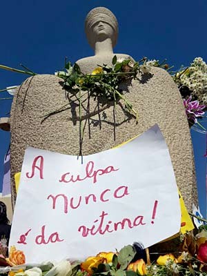 Estátua da Justiça, em frente ao STF, com flores e cartaz dizendo que a culpa nunca é da vítima  (Foto: Raquel Ribeiro/Arquivo pessoal)