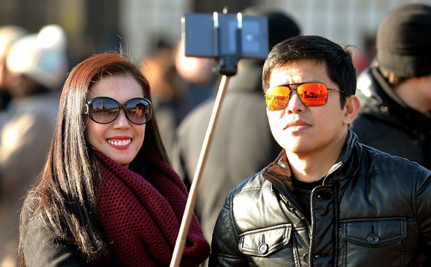 Casal tira foto com o 'pau de selfie' em Londres (Foto: John Stillwell/AP)