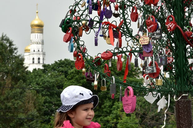 Garota ao lado de uma das Ã¡rvores de metal que abrigam os cadeados do amor em Moscou (Foto: Kirill Kudryavtsev/AFP)