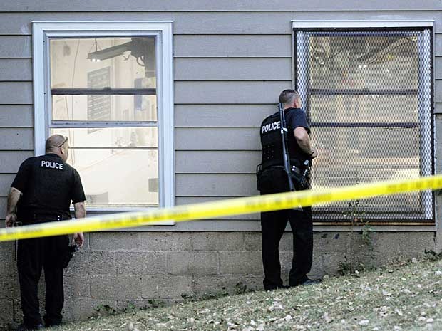 Policiais observam interior da empresa em Minneapolis onde um atirador abriu fogo. (Foto: Craig Lassig / AP Photo)