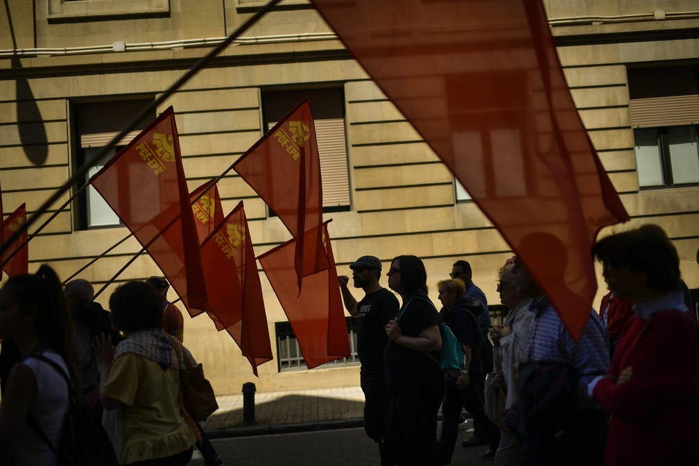 Pessoas carregam bandeiras comunistas durante protestos do 1º de maio em Pamplona, no norte da Espanha. — Foto: Alvaro Barrientos/AP