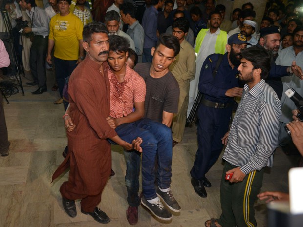 Vítima da explosão sendo socorrida depois que uma bomba explodiu em um parque público no Paquistão (Foto: Arif Ali/ AFP)