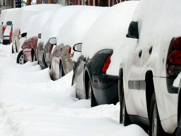 Morador de Washington retira neve; carros ficaram cobertos (Foto: AP)