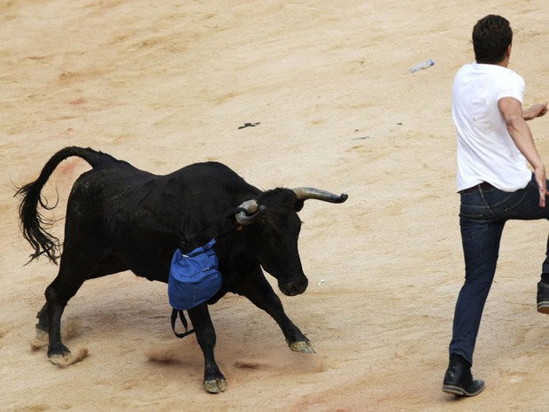 12 de julho - Touro 'roubou' a mochila de um corredor. A bolsa ficou presa em seu chifre enquando o rapaz tentava fugir do animal (Foto: Joseba Etxaburu/Reuters)