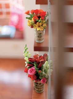 Para deixar a escada em clima de festa, a anfitriã preparou arranjos de flores em porta-velas de vidro