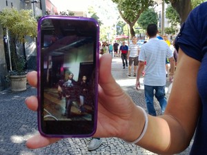 Moradora que não quis se identificar mostra fotos de seu celular de jovens saqueando a loja (Foto: Lilian Quaino/G1)