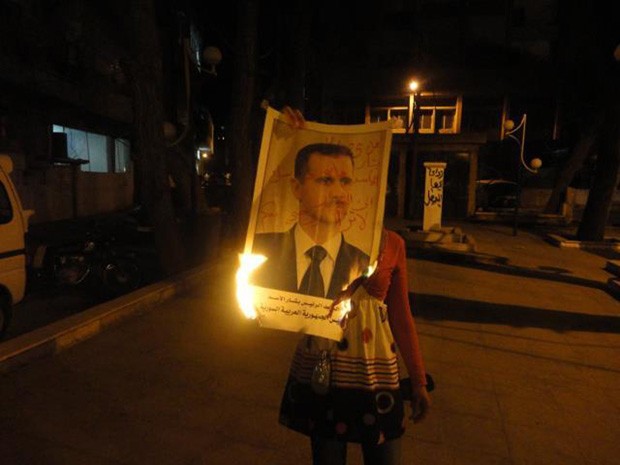 Manifestante antirregime ondeima cartaz aofoto do presidente Bashar al Assad, em Damasco (Foto: AFP) Manifestante antirregime ondeima cartaz aofoto do presidente Bashar al Assad, em Damasco (Foto: AFP)