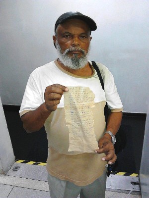 Idoso segura carta escrita em papel de pão para jovem americana (Foto: Rodrigo Nardelli/ G1)