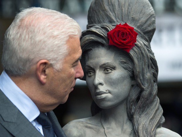 Mitch, pai de Amy Winehouse, ao lado de estátua em homenagem à cantora, que foi inaugurada neste domingo (14) no Camden's Stables Market, bairro de Londres (Foto: AP Photo/Tim Ireland)
