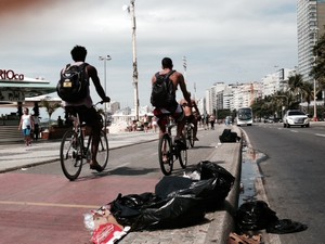 Apesar do trabalho dos garis nesta sexta, alguns sacos de lixo ainda dividiam o espaço com ciclistas na orla de Copacabana, altura do posto 5 às 10h. (Foto: Guilherme Brito / G1)