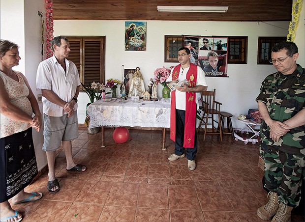 ORAÇÕES Um capelão da polícia paraguaia (centro) reza uma missa na casa dos Ficks, no fim de outubro. “Se Arlan morrer, nunca mais terei fé”, diz Alcido (Foto: Rogério Cassimiro)