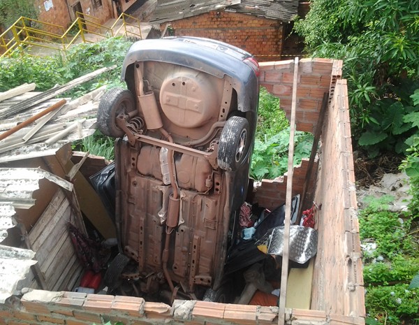 Veículo ficou de ponta cabeça aós cair encima de residência no Sacavém. (Foto: Domingos Ribeiro)