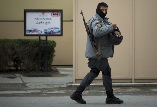 Policial afegão guarda a entrada do hotel Serena em Cabul, no Afeganistão, nesta sexta-feira (21). Homens armados invadiram o local e abriram fogo, matando pelo menos nove pessoas (Foto: Anja Niedringhaus/AP)