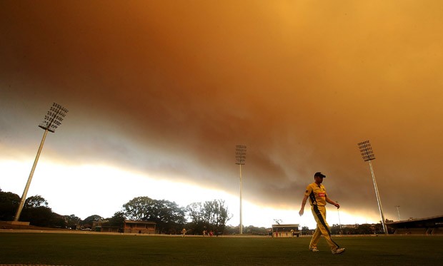 Homem observa fumaça cobrindo campo de críquete em Sydney (Foto: Mark Metcalfe/Getty Images)