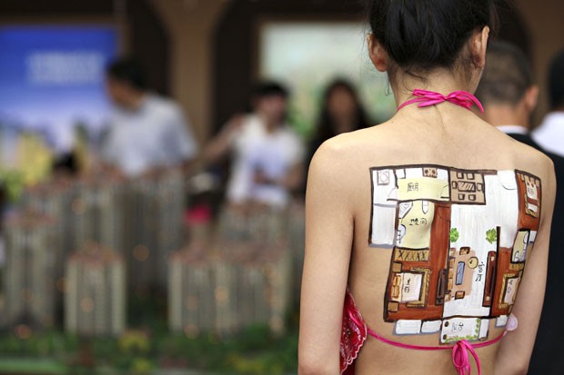 Modelo exibe pintura corporal em forma de planta de apartamento em feira na China (Foto: Xinhua, Cui Genyuan/AP)