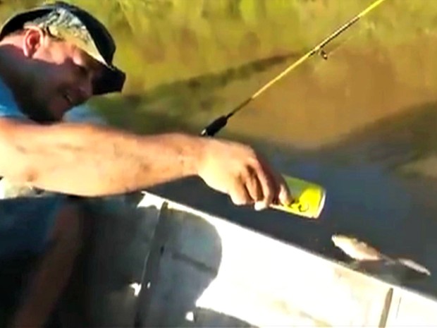 Pescador dá cerveja para peixe em barco (Foto: Reprodução)